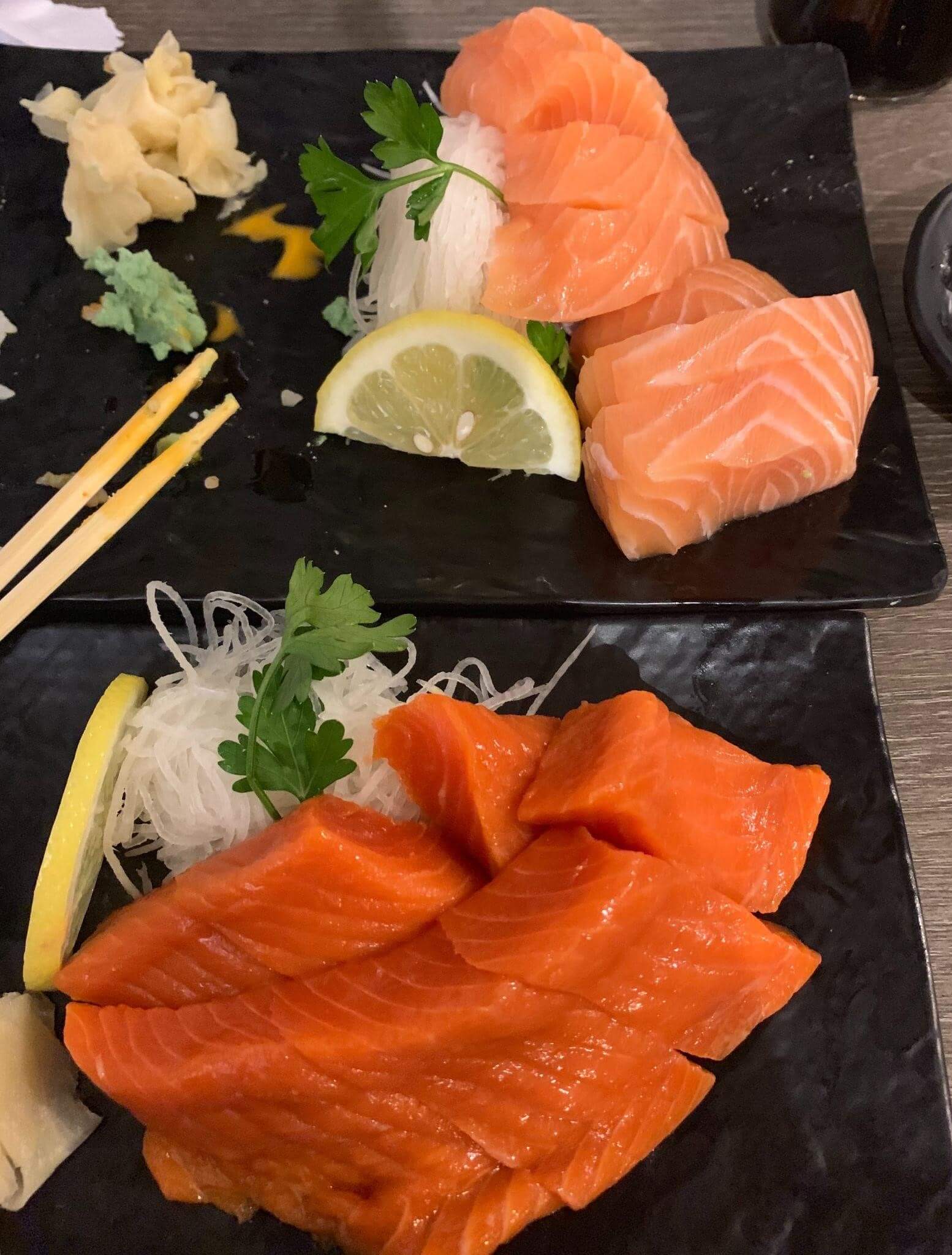 A plate of sashimi with pickled ginger and wasabi paste