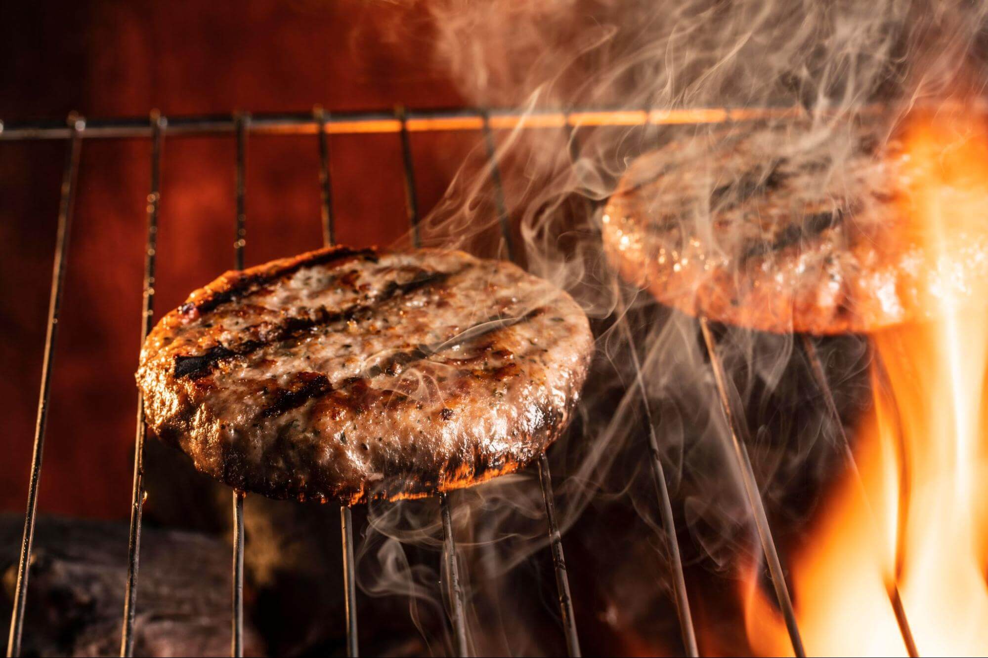 Beef patty grilling over hot fire